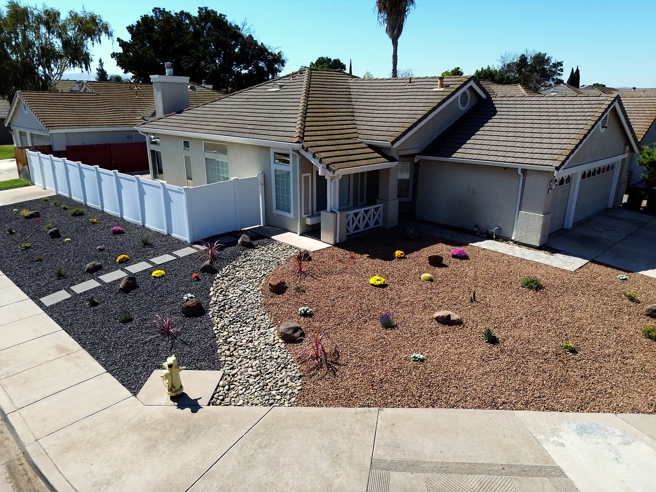 Drone view of a finished front: rock and mulch beds with new plants, edged along the walk