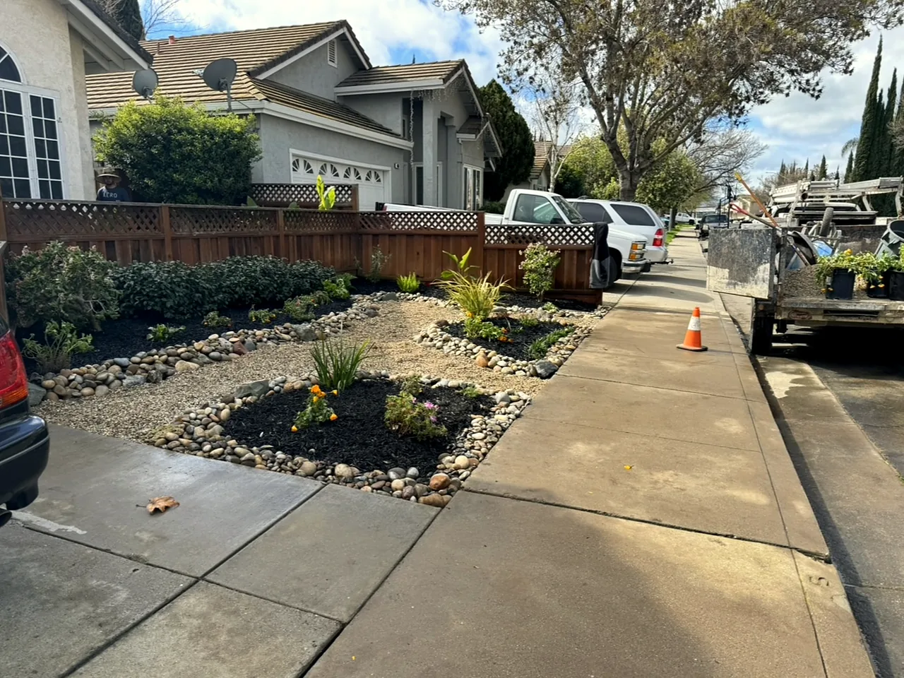 The same front finished: river rock borders, black mulch beds and new plants