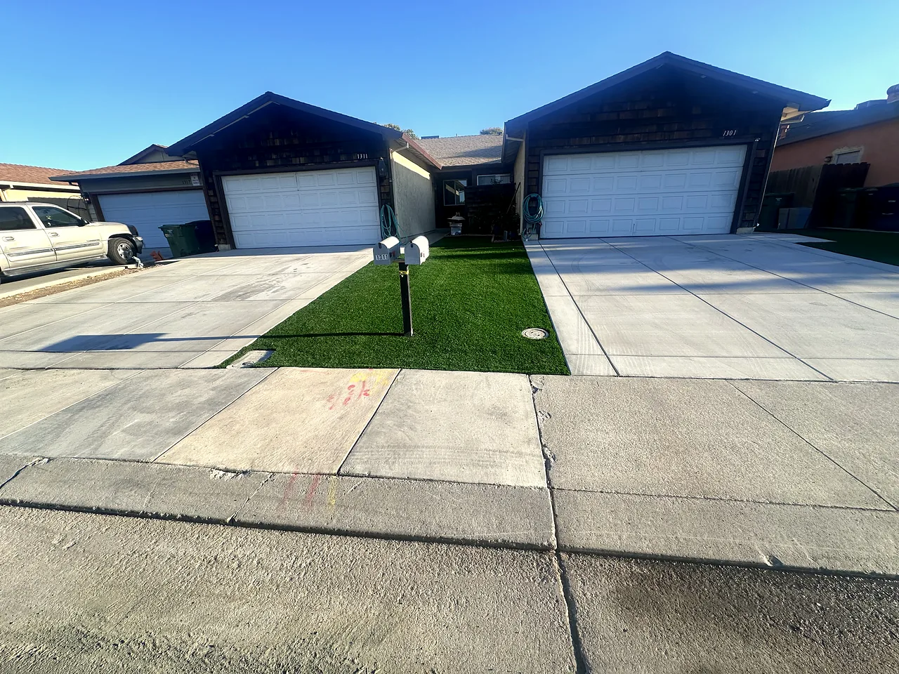 Duplex front finished: two new concrete driveways split by a band of artificial grass