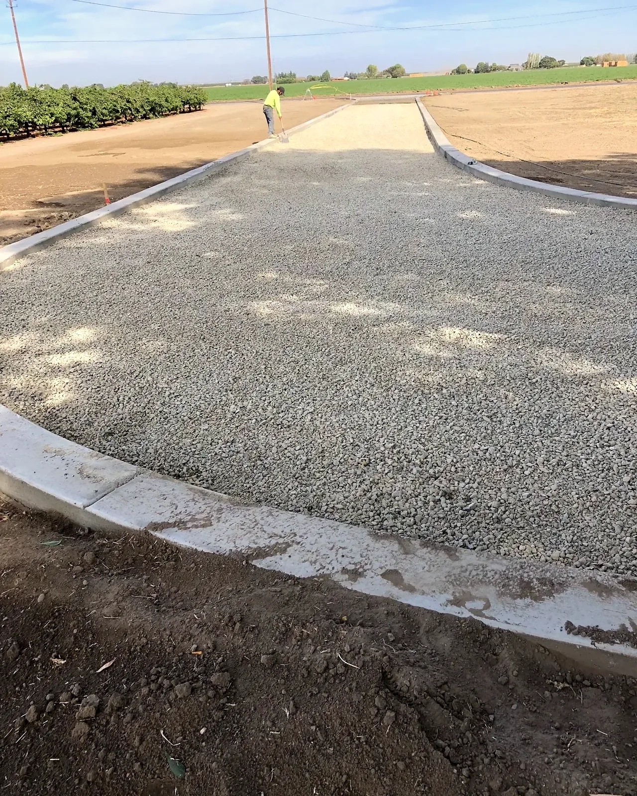 A gravel driveway finished between new poured concrete borders