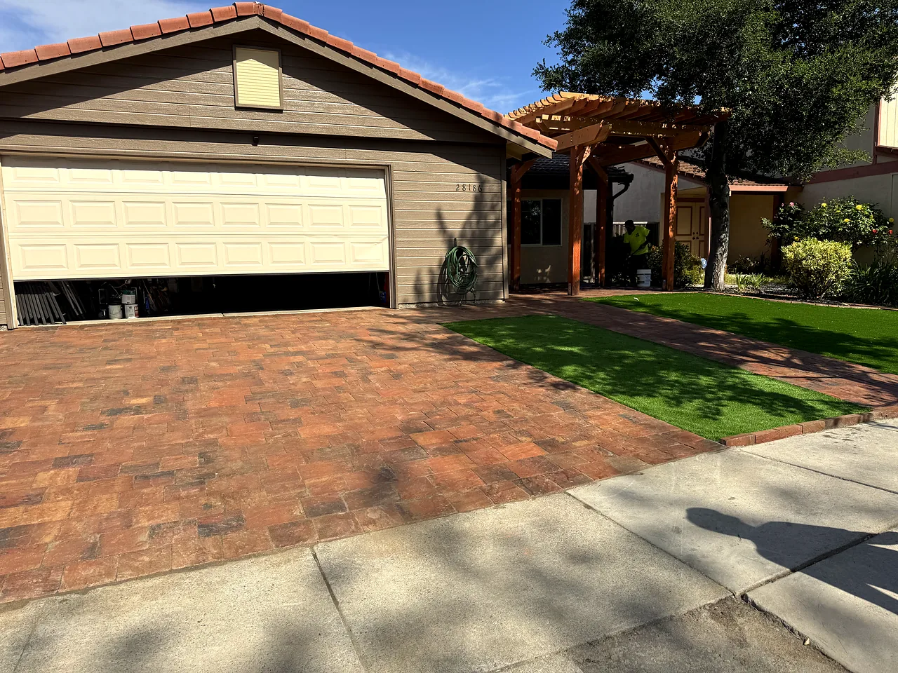 Front yard after: red paver driveway, artificial turf and a new wood pergola over the entry