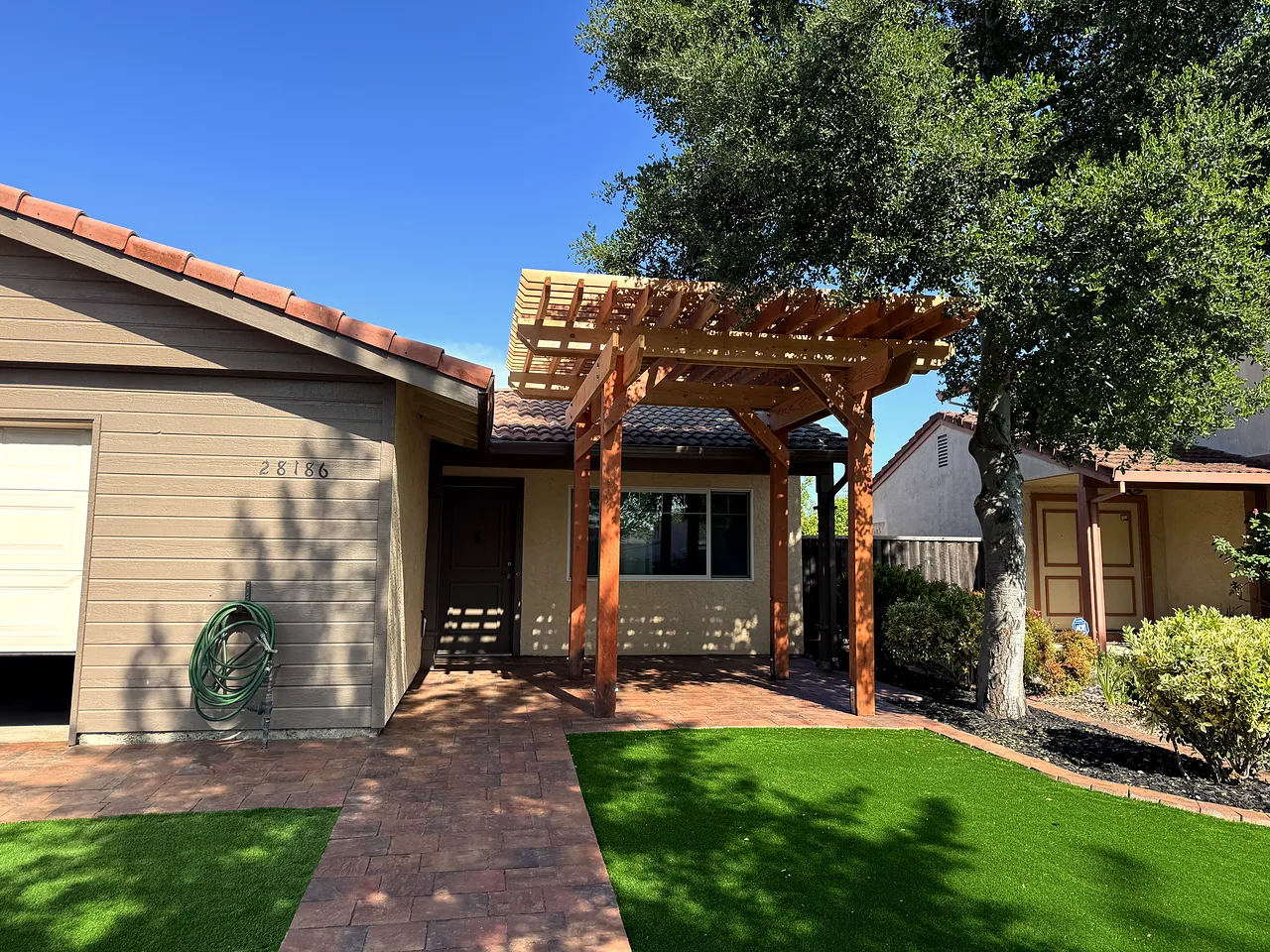 Paver walkway under the new pergola, lined with artificial turf