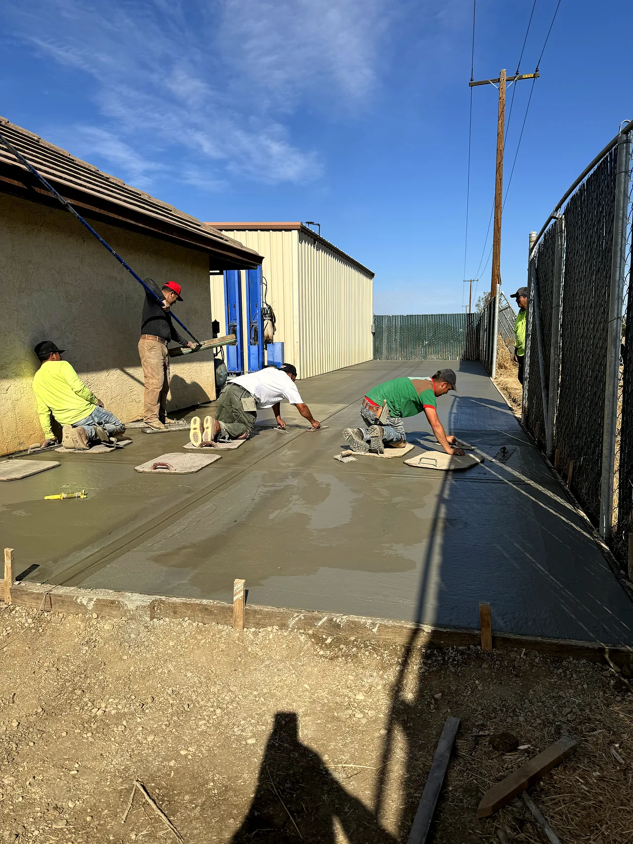 The crew screeding and finishing a concrete pour along the house